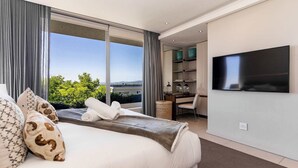 Ein modernes Hotelzimmer mit einem großen Bett, einem an der Wand montierten Fernseher und Blick auf die Stadtlandschaft.