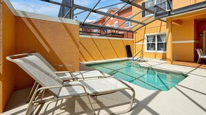 A pool area with a clear view of the sky, a pool, and a chair.