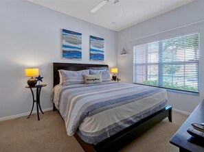 A bedroom with a bed, two bedside lamps, a nightstand, a window with blinds, and two wall art pieces. - Adorable townhome remodeled with comfort and relaxation in mind! Splash Pool! (Kissimmee)