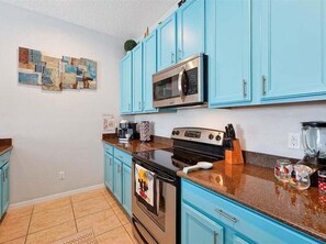A kitchen with blue cabinets, a microwave, an oven, and a coffee maker. - Adorable townhome remodeled with comfort and relaxation in mind! Splash Pool! (Kissimmee)