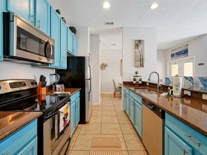 A kitchen with blue cabinets, a microwave, stove, refrigerator, and a sink. - Adorable townhome remodeled with comfort and relaxation in mind! Splash Pool! (Kissimmee)