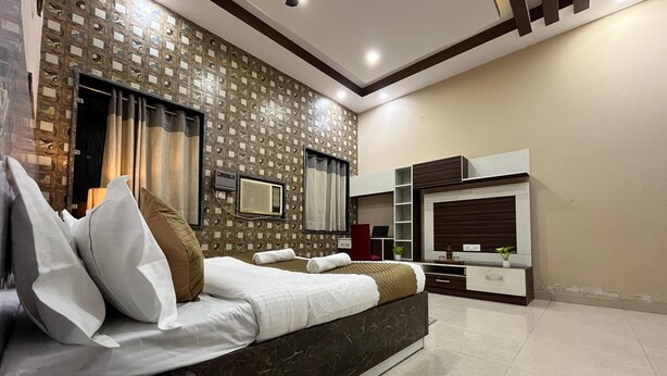 A modern bedroom with a large bed, a TV, a built-in shelf, and a patterned wall.