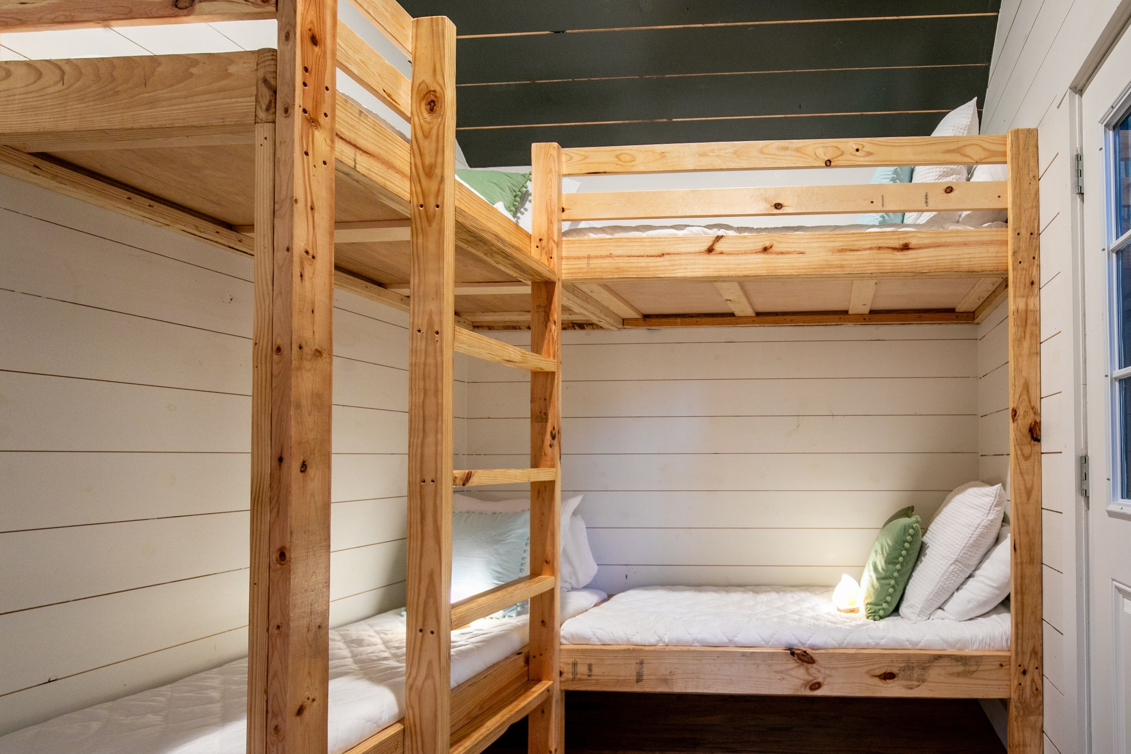 A bunk bed room with wooden frames and white bedding.