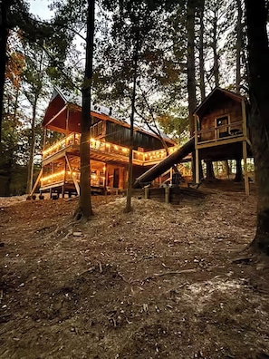 A multi-story wooden cabin with a balcony, surrounded by trees.
