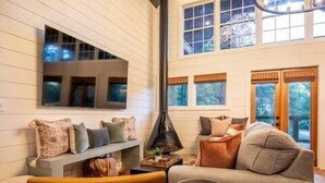 Una sala de estar acogedora con chimenea, un sofá, una mesa de centro y un banco con cojines.