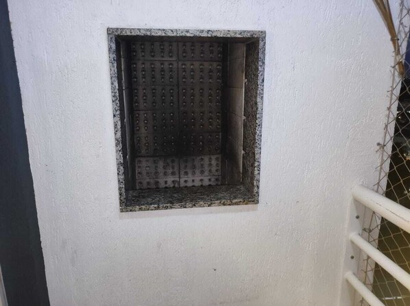 A window with a metal grid, a white wall, and a metal railing.