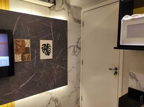 Un baño con pared de mármol, un lavamanos y una puerta.