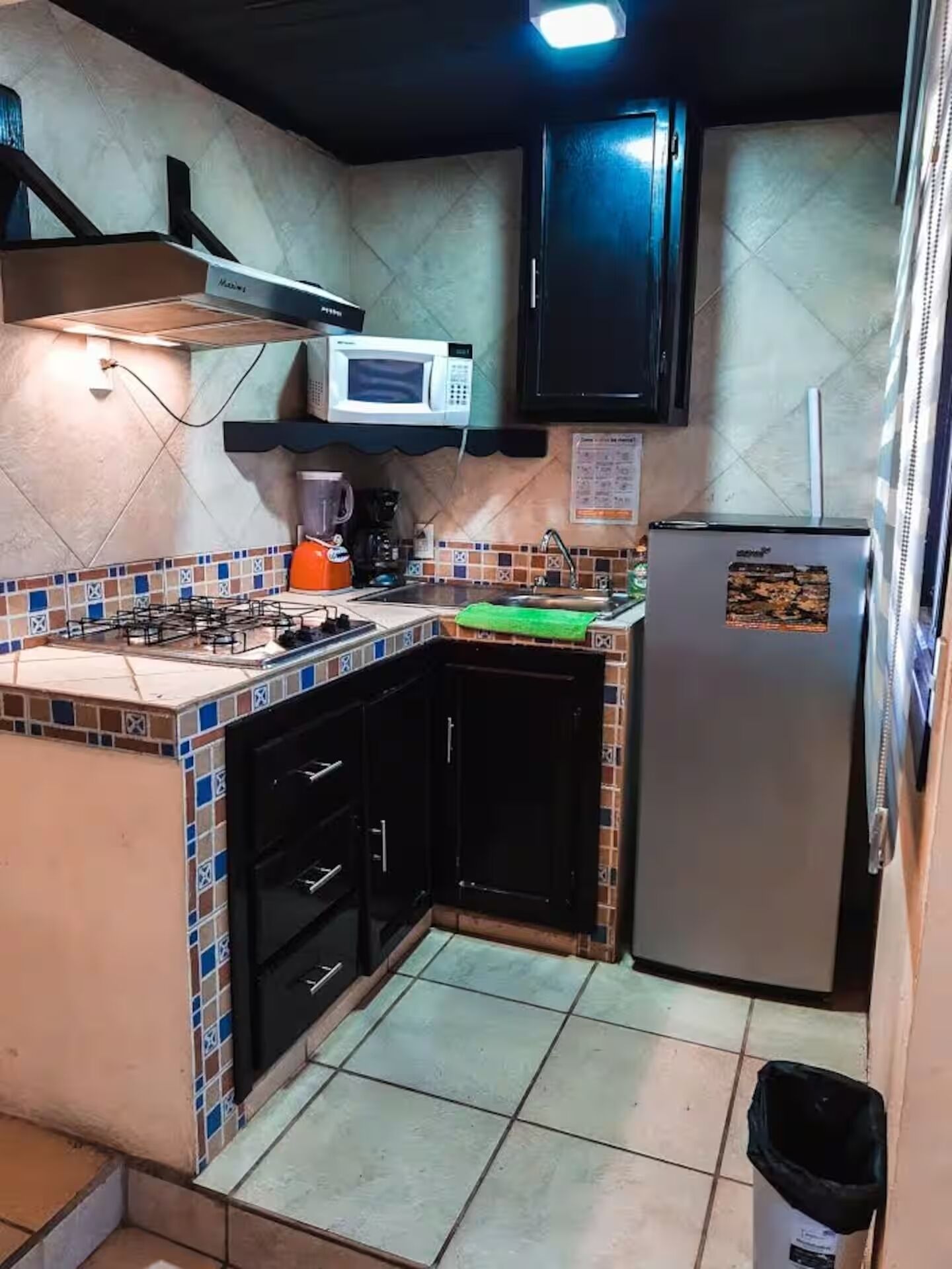 Una cocina compacta con microondas, cafetera y refrigerador.