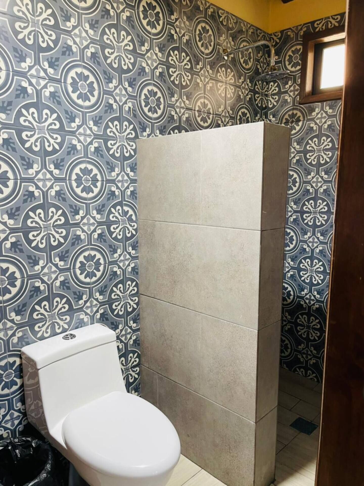Un baño con inodoro, cabina de ducha y azulejos decorativos en las paredes.
