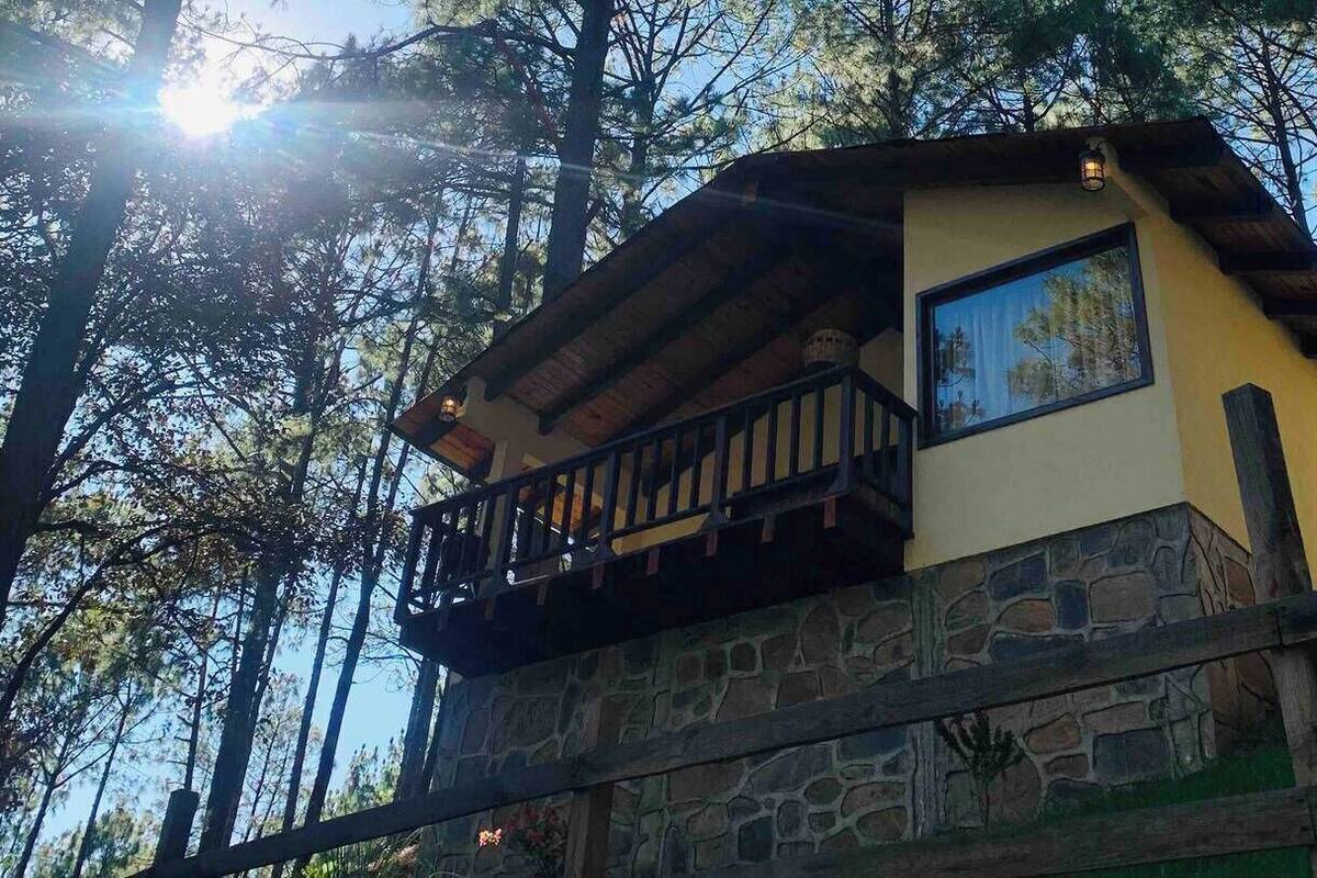 Une cabane avec une base en pierre, un balcon et une grande fenêtre.
