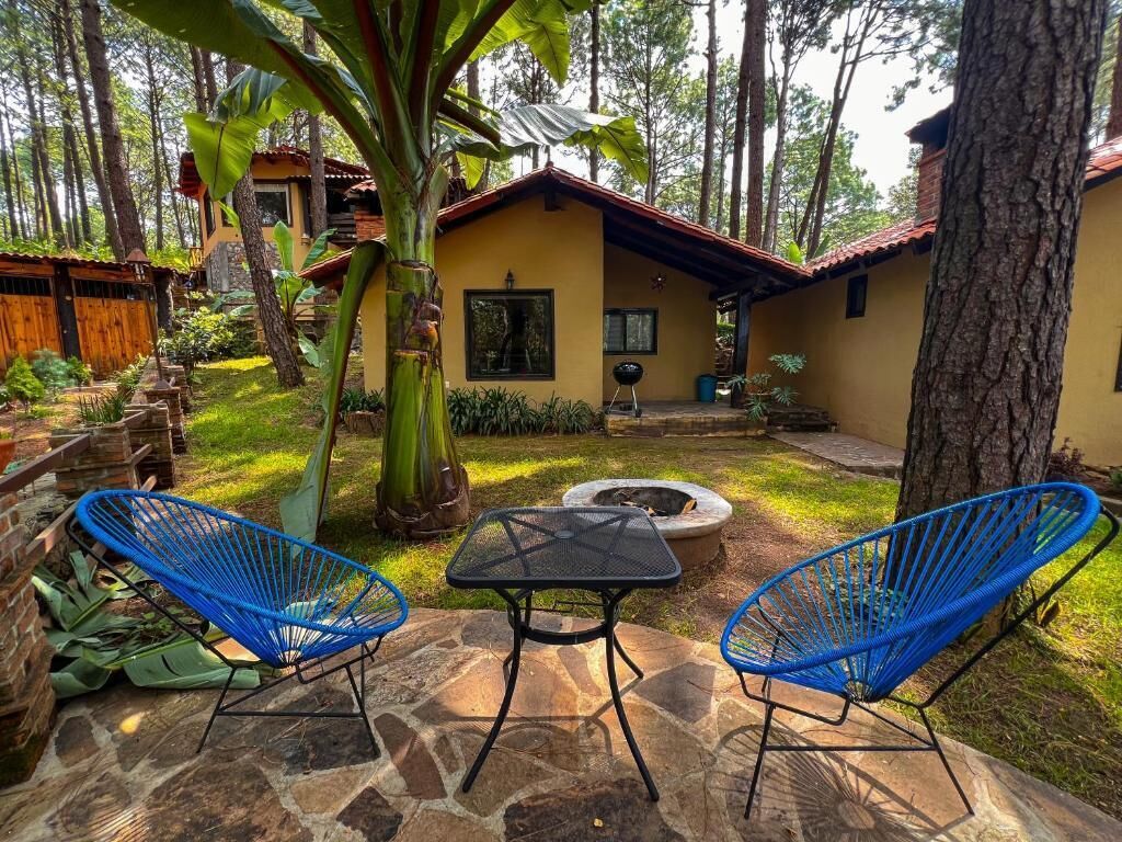 A patio area with two blue chairs, a stone table, and a fire pit.