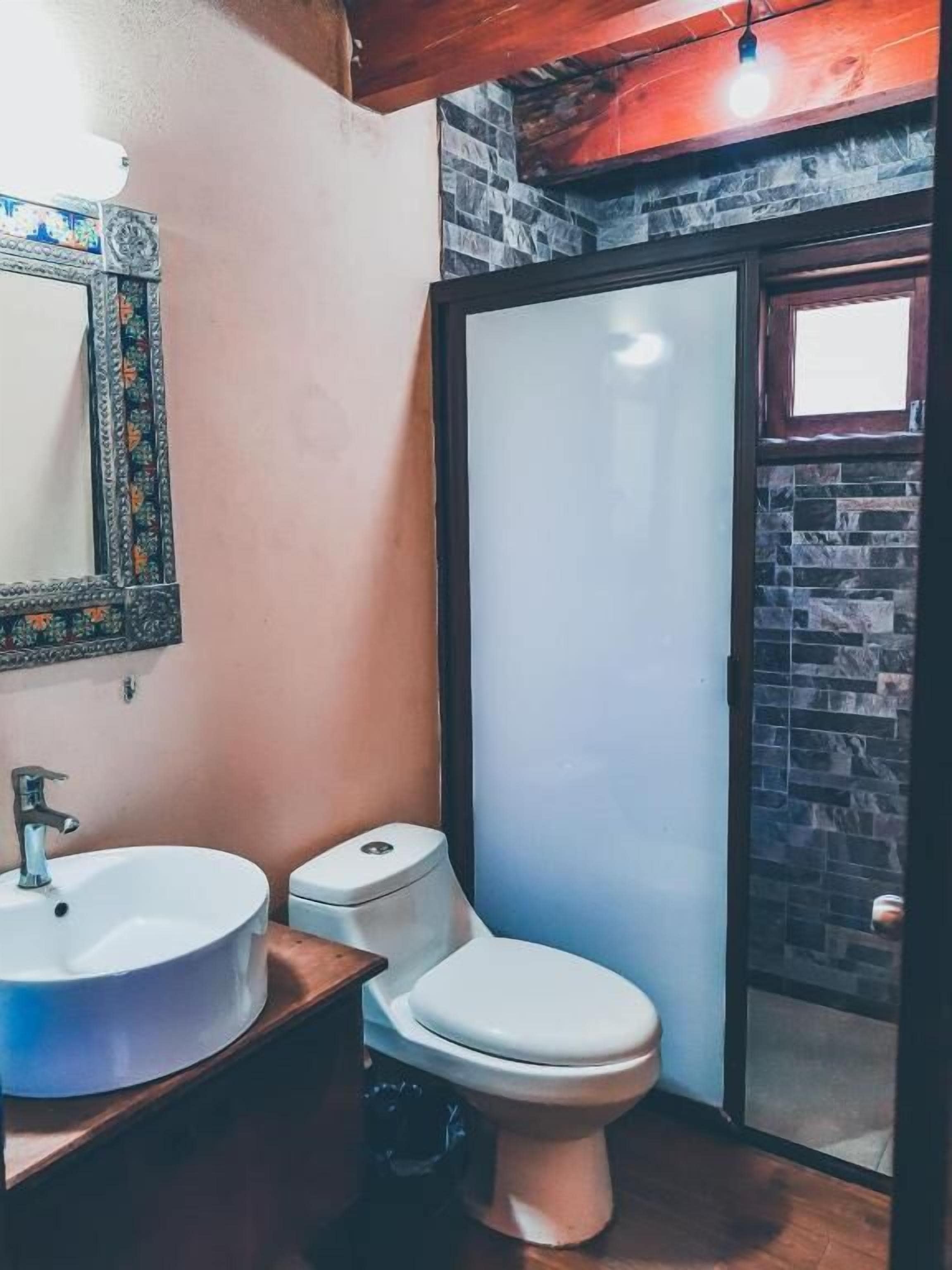Une salle de bain avec un lavabo blanc, des toilettes et un miroir doté d’un cadre décoratif.