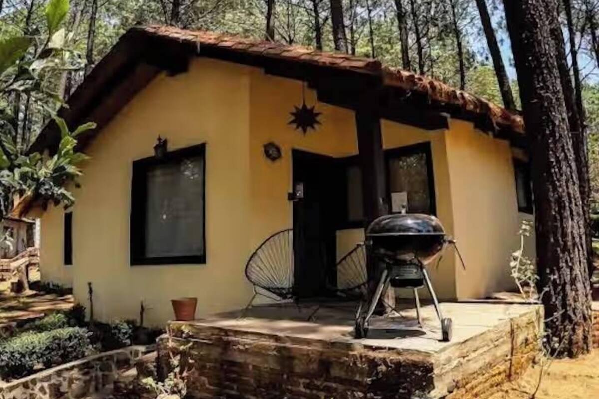 Un petit bâtiment d’un seul étage, doté d’un toit en pente, d’un porche avec un barbecue et d’une chaise.