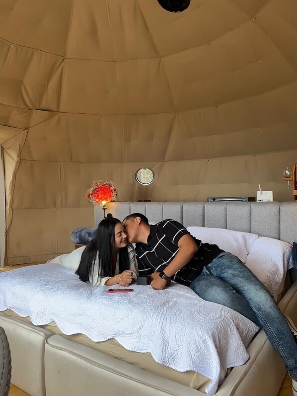 Una habitación con carpa, una cama, una mesita y una ventana.