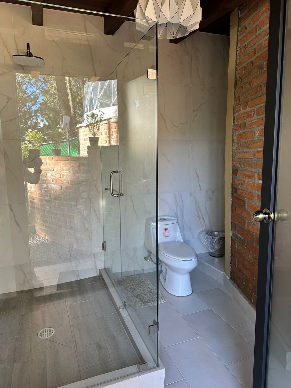 A modern bathroom with a glass-enclosed shower, a toilet, and a sink.