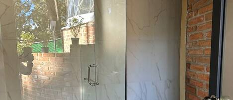 A modern bathroom with a glass-enclosed shower, a toilet, and a sink.