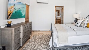 Une chambre à coucher comprenant un lit, une commode, un t éléviseur et un ventilateur de plafond.