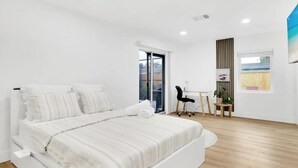 Une chambre à coucher moderne avec un grand lit, un bureau et une chaise.