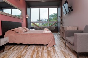 A bedroom with a bed, a hammock, a TV, and a chair. - Hotel El Mesón  (La Dorada)