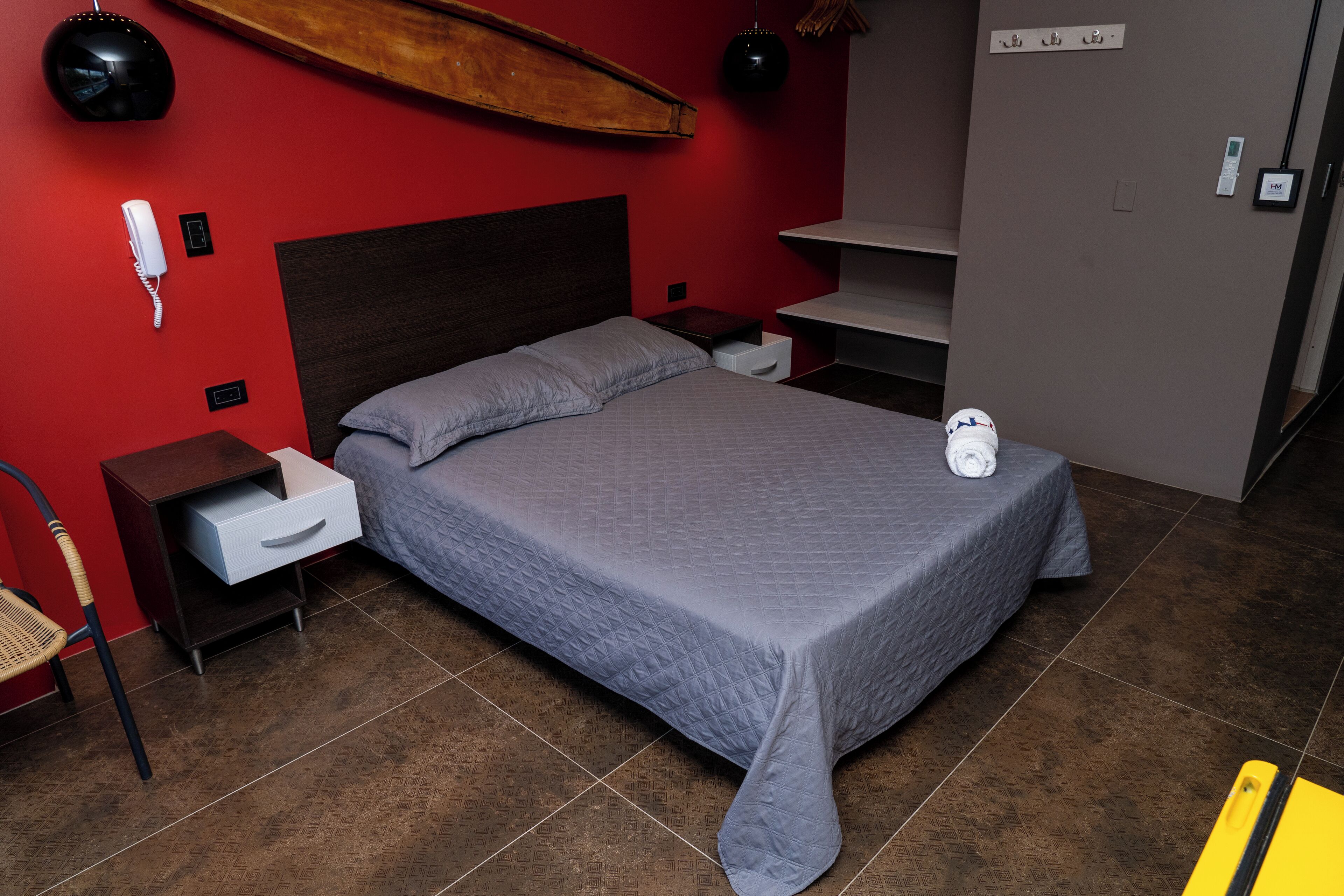 A neatly arranged bedroom with a bed, bedside tables, a chair, and a wall-mounted telephone.