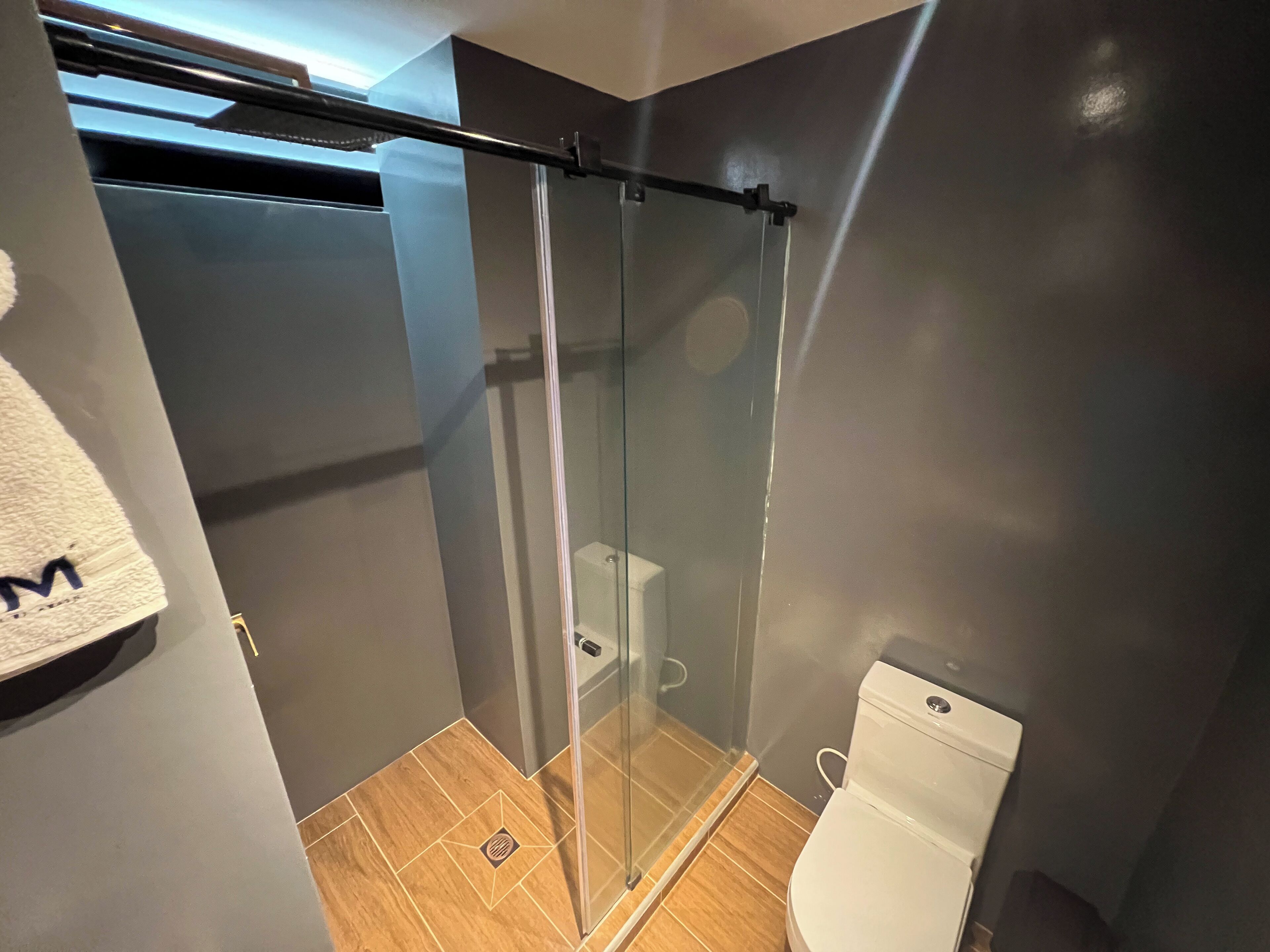 Un baño moderno con cabina de ducha de vidrio, inodoro y perchero para toallas.