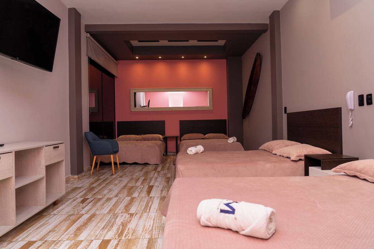A hotel room with two beds, a desk, a chair, a TV, and a mirror.
