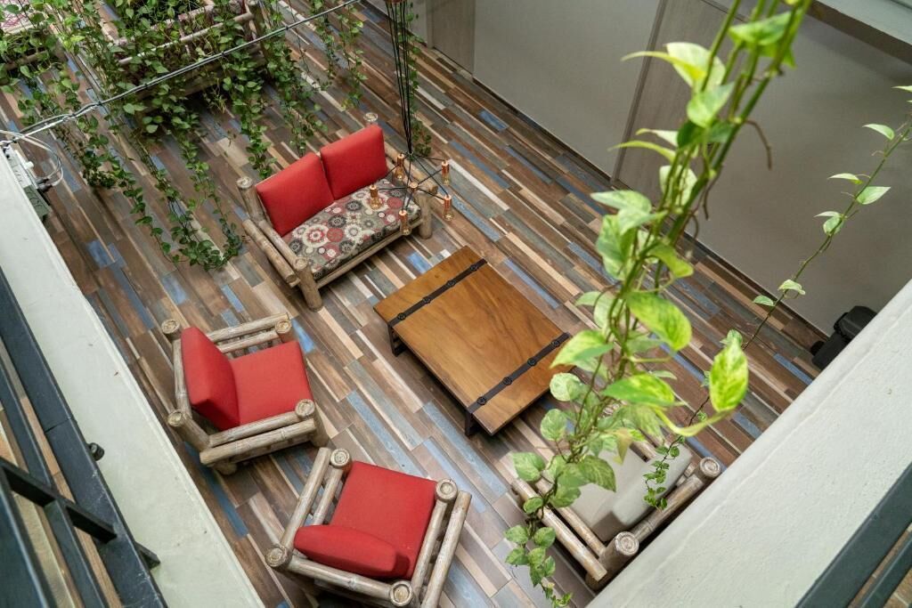 Una terraza en la azotea con piso de madera, asientos acolchados rojos y una pequeña mesa.