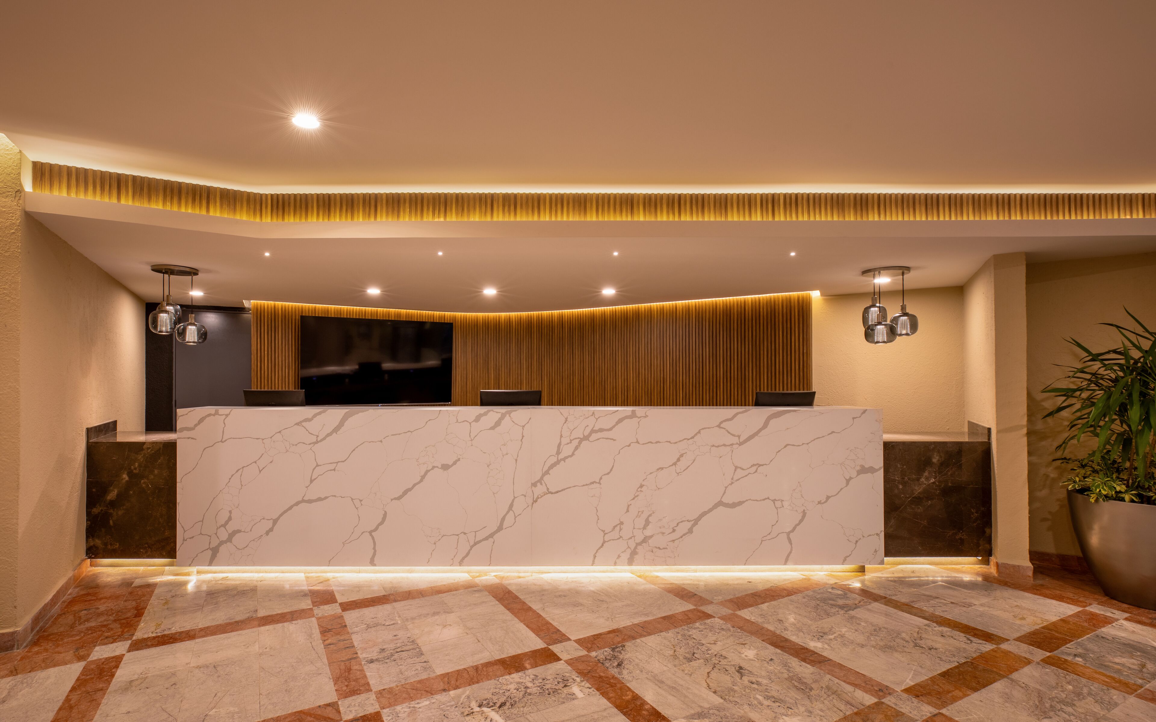 A reception area with a marble counter, a large flat-screen TV, and a checkered floor.