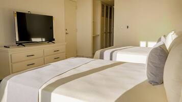 A hotel room with two beds, a TV on a dresser, and a walk-in closet.