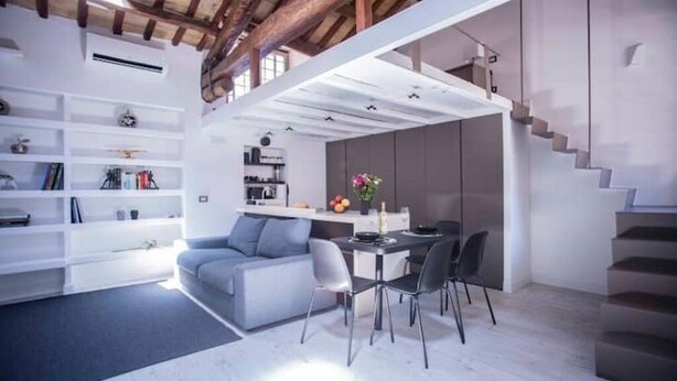 A modern interior with a dining area, kitchen, and a staircase. - Mad Hatter (Roma)