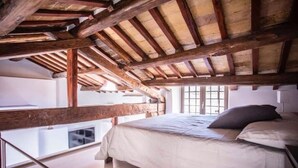 A bedroom with a wooden ceiling, a bed, and a window. - Mad Hatter (Roma)