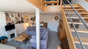 A modern living room with a fireplace, sofas, a coffee table, and a staircase. - Magnificent Holiday Home for 6 Adults in Xhoffraix (Malmedy)