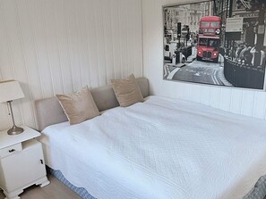 Ein Schlafzimmer mit einem großen Bett, einem Nachttisch, einer Lampe und einem Stadtplakat an der Wand.