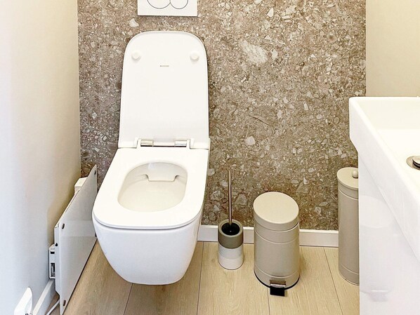 Un baño con inodoro blanco, un bidé y dos cestos de basura.
