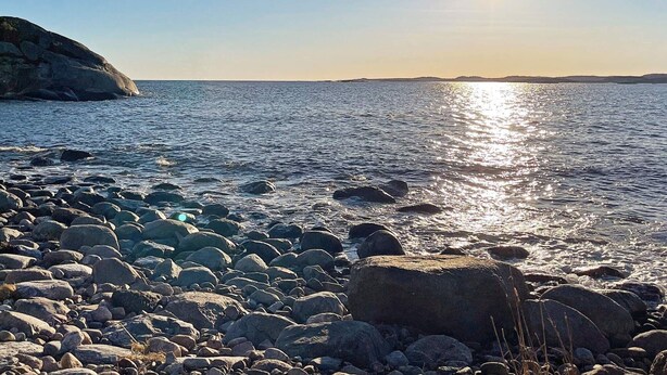 Une côte rocheuse où le soleil se reflète sur l’eau.