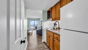 A kitchen with wooden cabinets, a white refrigerator, and a microwave. - Bluewater Resort 207 (Myrtle Beach)
