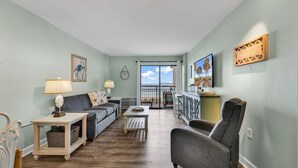 A living room with a sofa, armchair, coffee table, and a view to the outside. - Bluewater Resort 207 (Myrtle Beach)
