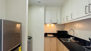 A compact kitchen with a refrigerator, stove, sink, and cabinets. - Exclusive 1BR Residences at LaFayette Park Square (Iloilo City)