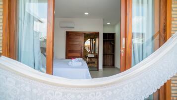 Una habitación con una cama, una puerta de madera, un armario y una ventana con cortinas.
