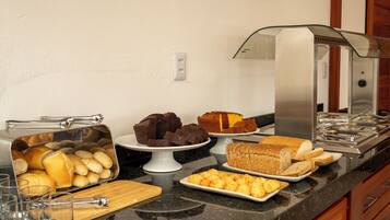 A buffet setup with various baked goods, including bread, pastries, and muffins.