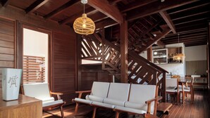 Een houten interieur met een bank, houten stoelen en een trap.