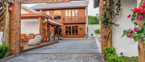A villa with a wooden facade, a covered patio, and a sign reading "Villa do Zé".