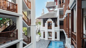 Un hotel de varios niveles con piscina central, balcones y un estilo arquitectónico tradicional.