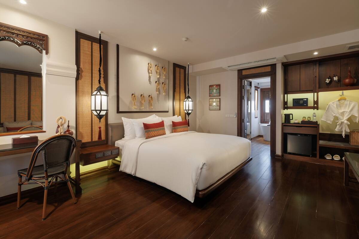 Um quarto espaçoso com uma cama grande, uma escrivaninha de madeira e uma cadeira.