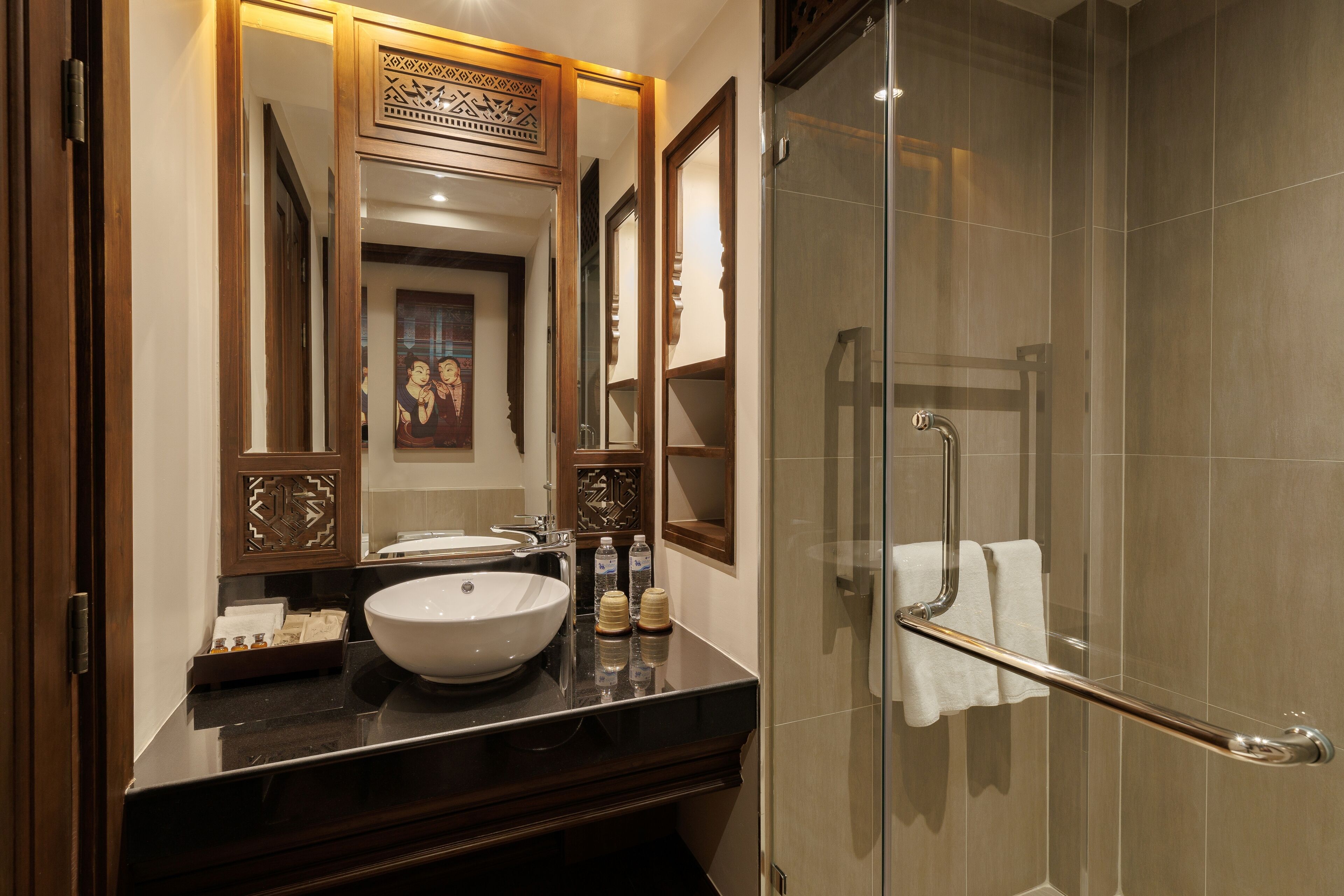 A modern bathroom with a large mirror, a vessel sink, and a glass-enclosed shower area.