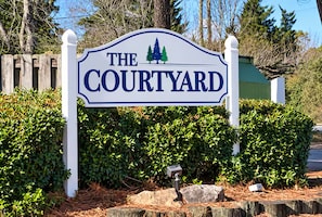 A sign for 'The Courtyard' with a simple design and a tree graphic. - Corporate Retreat: Stylish 2BR, Pool, Balcony (Wilmington)