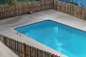 A rectangular swimming pool with a wooden fence surrounding it.