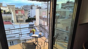 A balcony with a table, chairs, and a potted plant.