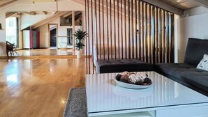 A modern living room with a glass coffee table, a dark sofa, and a decorative light fixture.