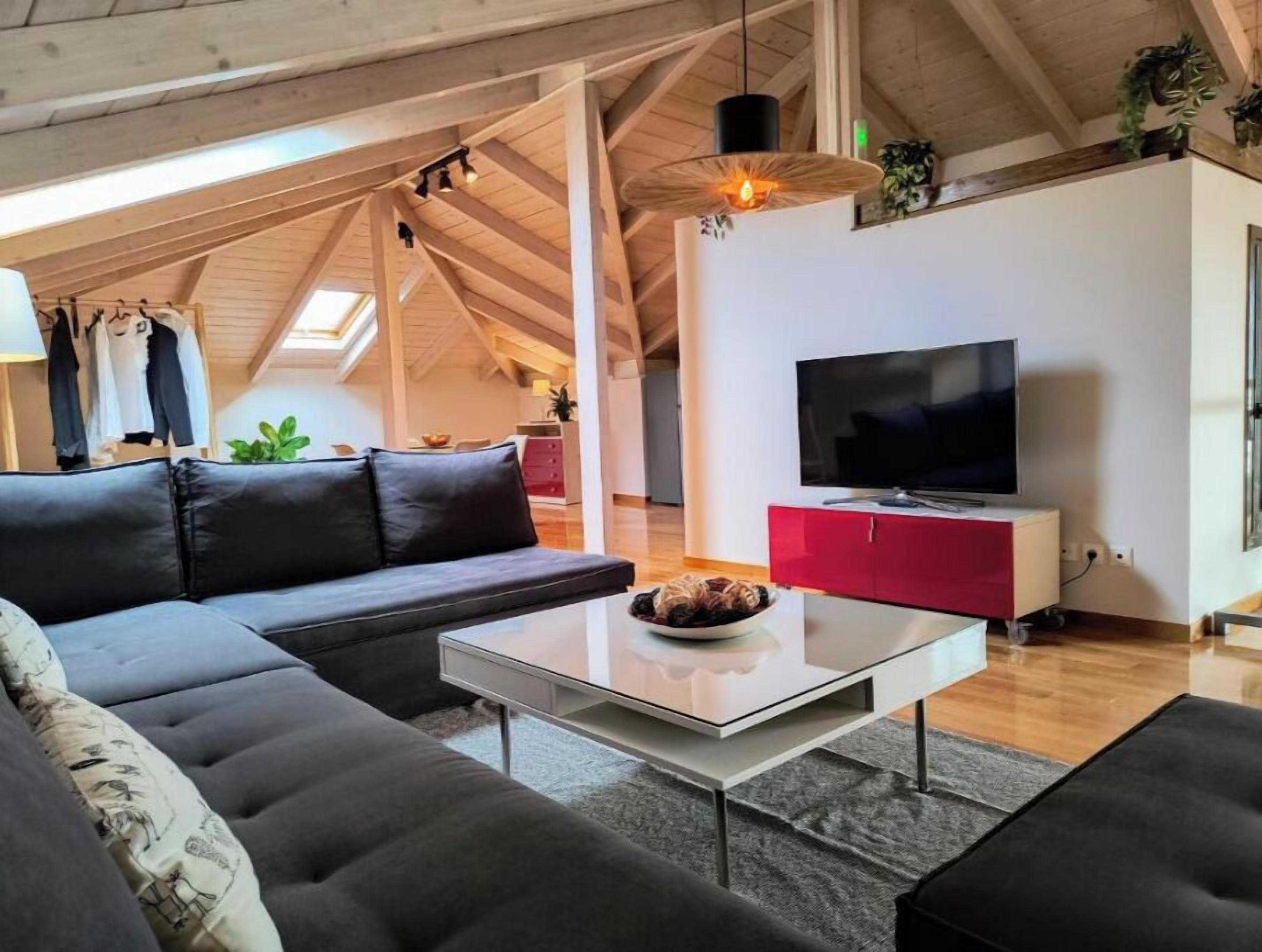 Ein modernes Wohnzimmer mit einer schwarzen Couch, einem Glastisch und einem roten Schrank mit einem Flachbildfernseher.